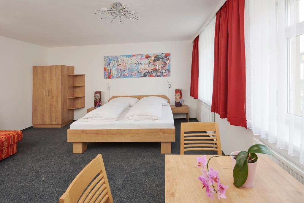 Modernes Studio-Apartment mit Doppelbett und Essbereich am Fenster