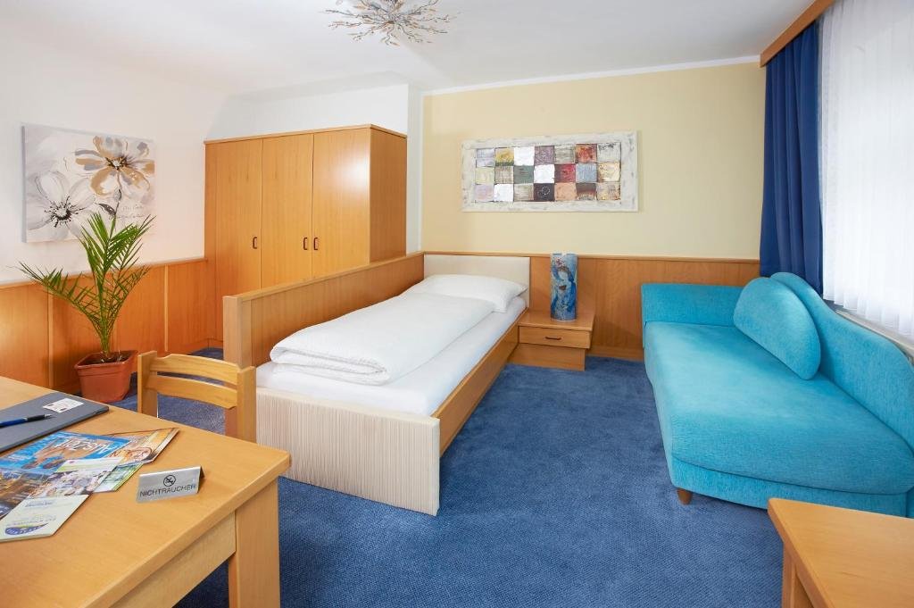 Komfortables Einzelzimmer mit Einzelbett, Sofa und Arbeitsbereich